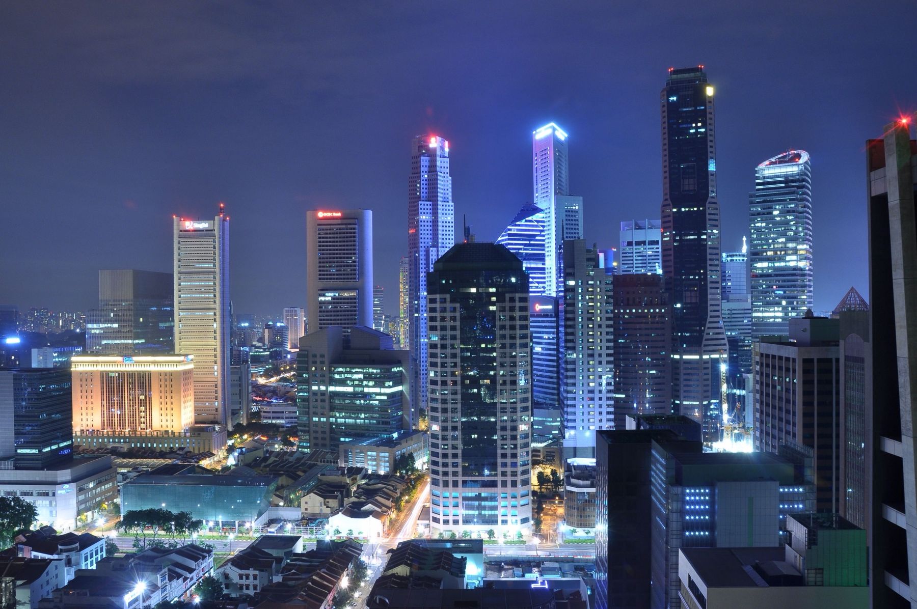 City towers rising behind rows of shophouses at night